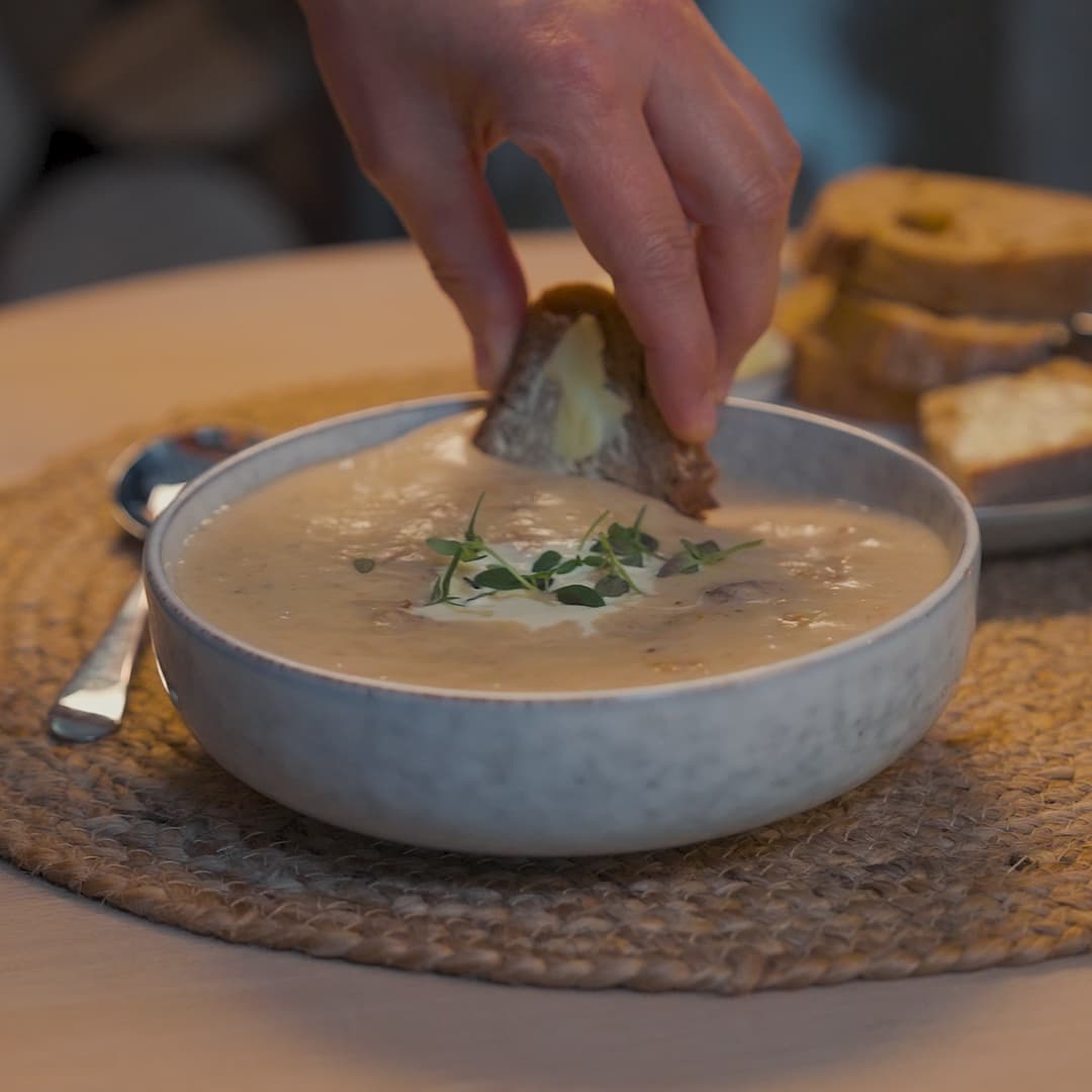 A bowl of cullen skink with bread being dunked into it