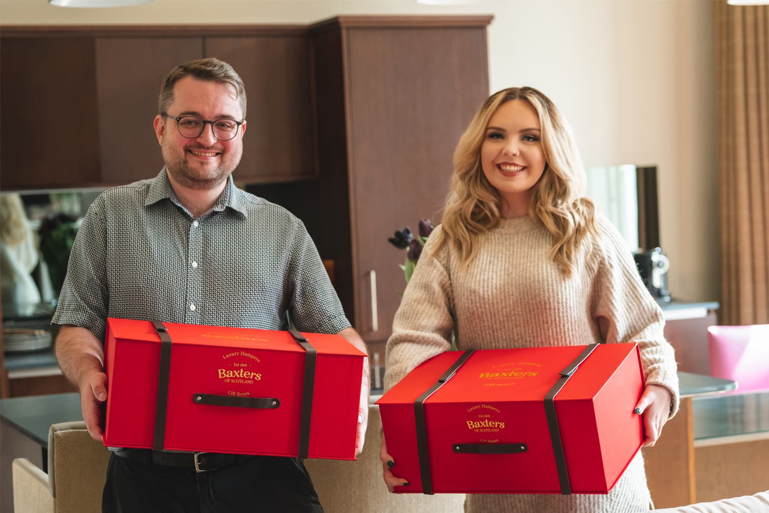 Two employees holding their corporate gift hampers